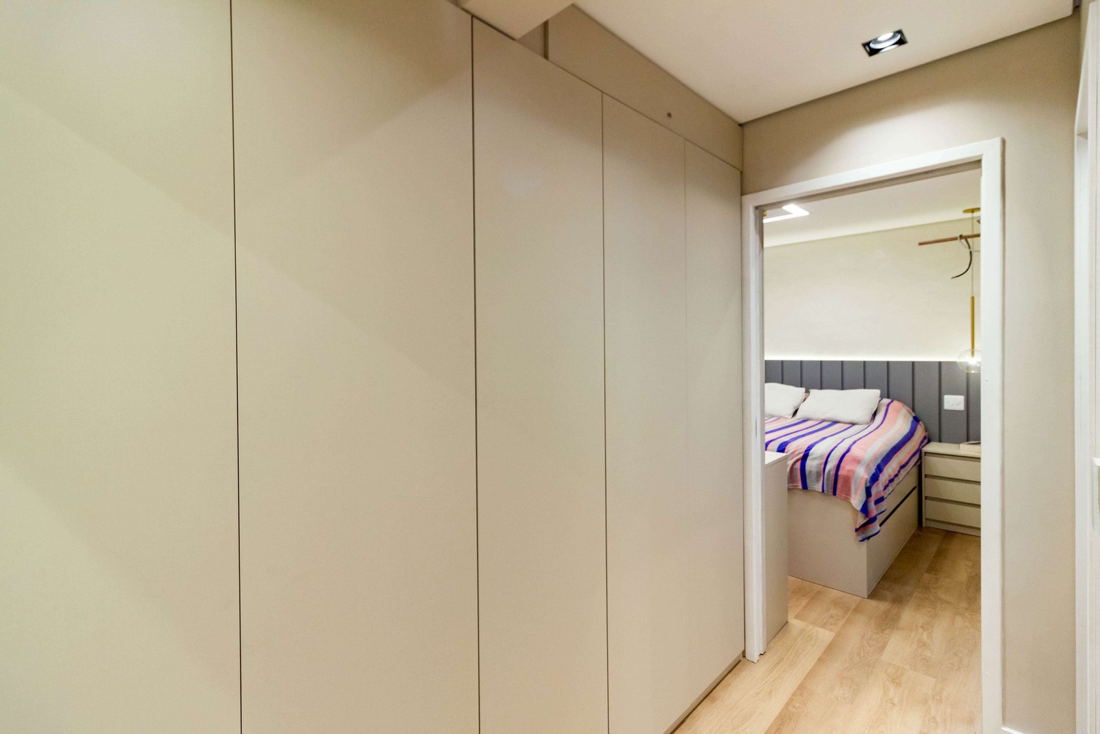 Detalhe dos armários do corredor (rouparia), mostrando o alinhamento perfeito da marcenaria e a continuidade do piso de madeira.