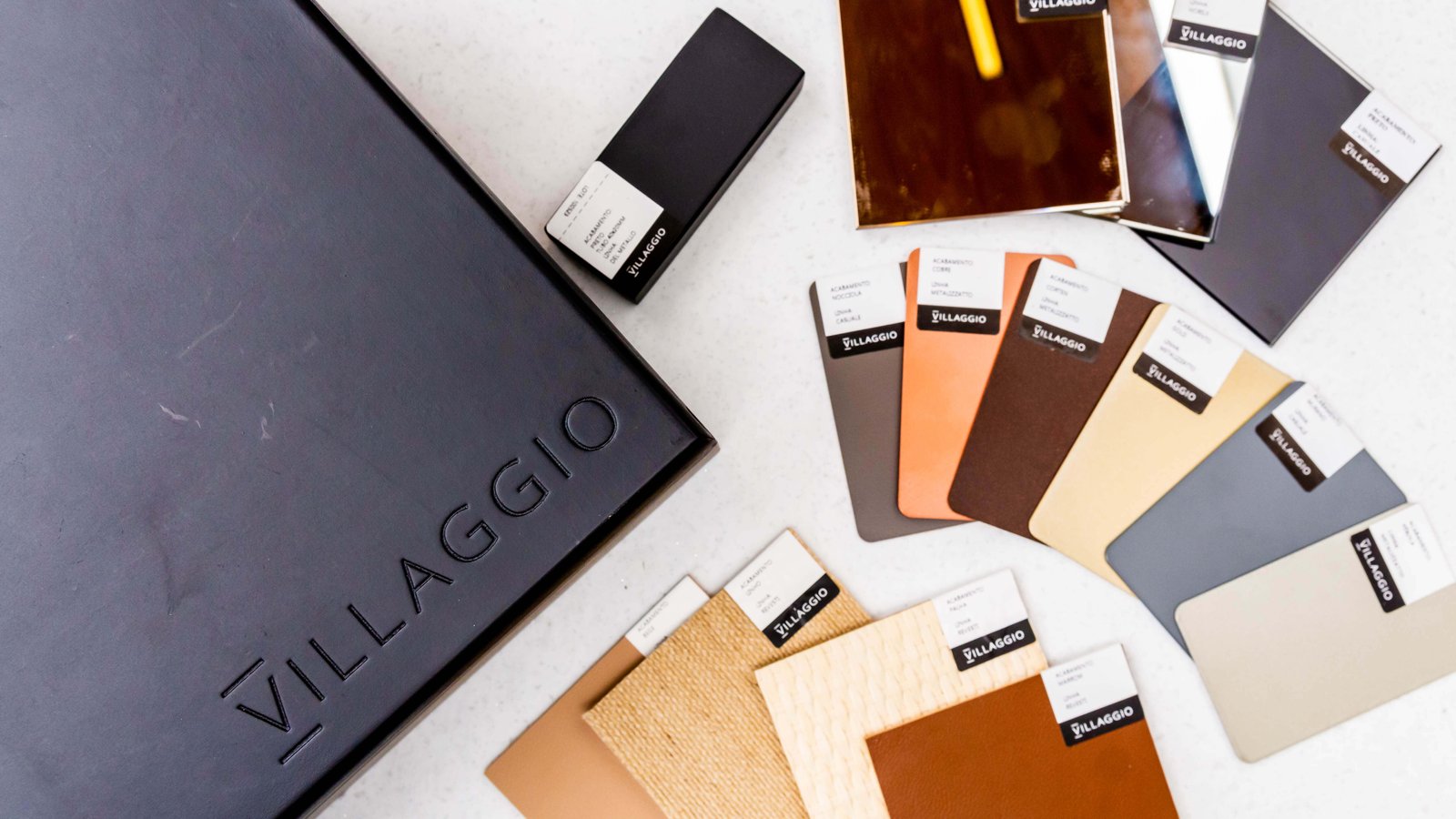 Conjunto de amostras de acabamentos e materiais da Villaggio para projetos de móveis sob medida, incluindo opções de madeira e cores sólidas.