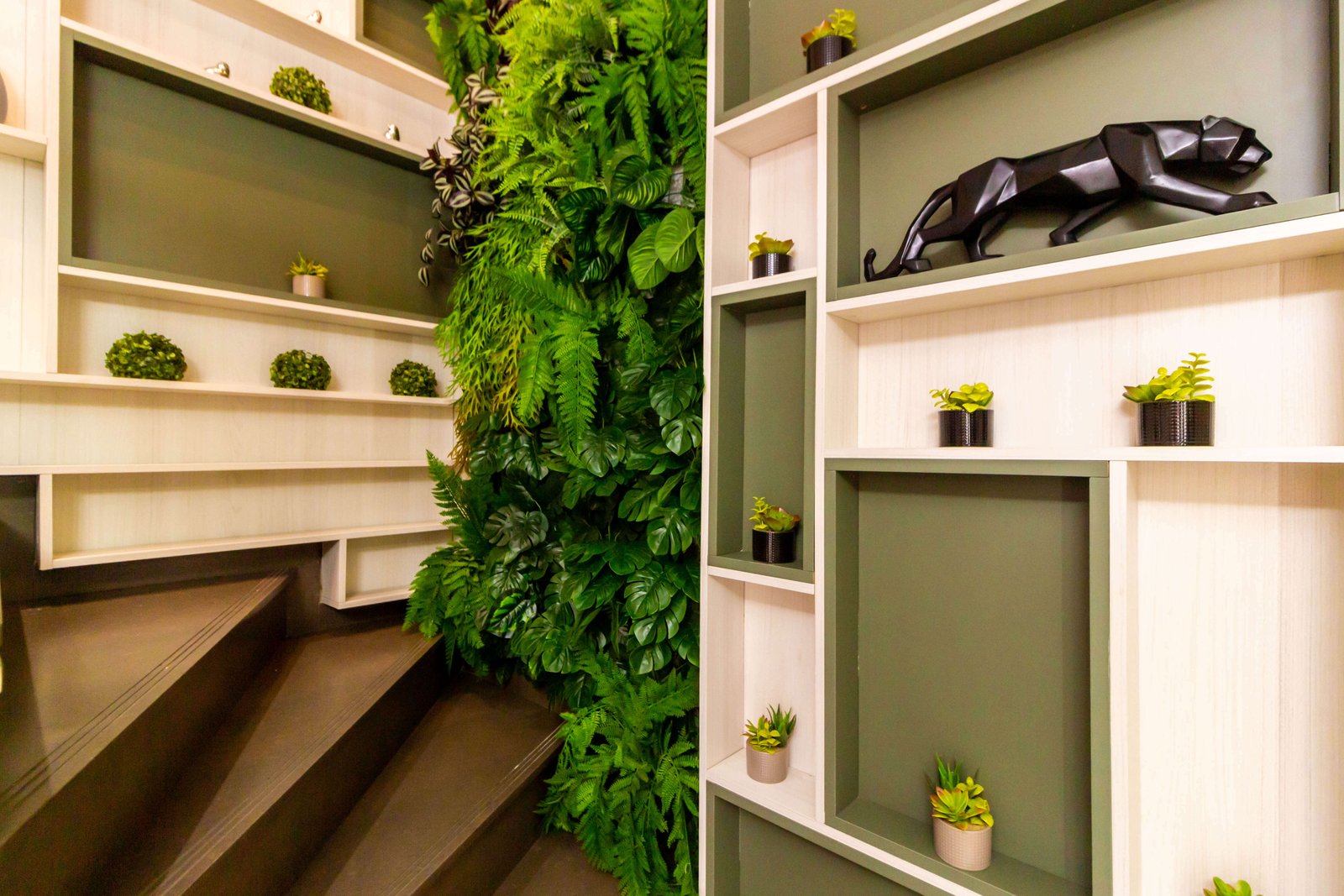 Vista ampla de ambiente planejado com pé-direito duplo, grandes janelas de vidro com vista para área verde, jardim vertical interno e mesa de jantar, demonstrando integração de espaços e marcenaria de alto padrão.